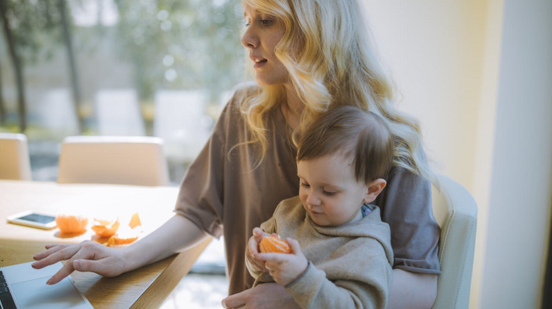 mom working on laptop while holding toddler