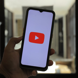 hand holding a phone with YouTube logo on the screen