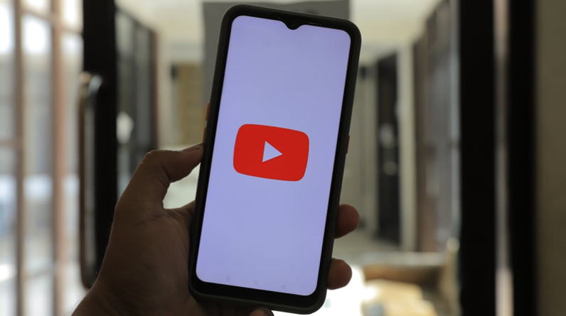hand holding a phone with YouTube logo on the screen