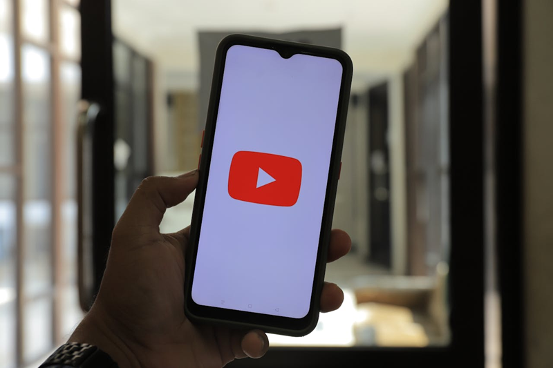 hand holding a phone with YouTube logo on the screen