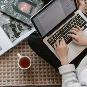 woman working on laptop while drinking a cup of tea