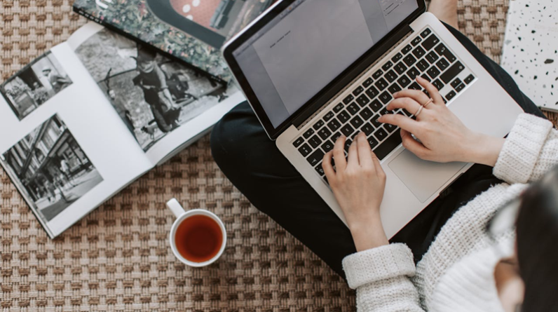 woman working on laptop while drinking a cup of tea