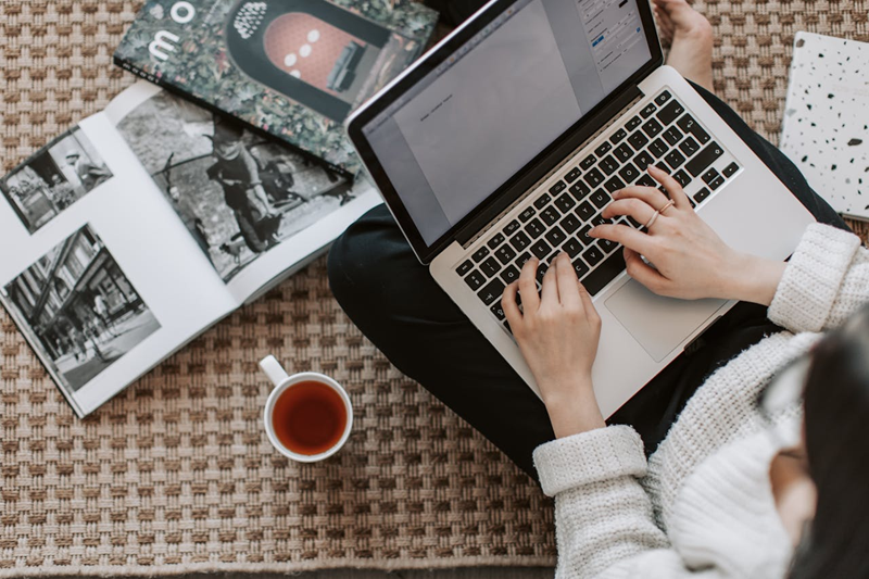 woman working on laptop while drinking a cup of tea